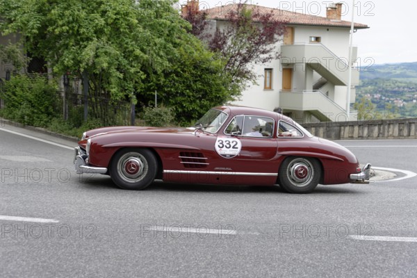 No. 332, Mercedes-Benz 300 SL W 198, model year 1955, Red classic car in a bend in front of a house with trees in the background, Mille Miglia 2014 or 1000 Miglia, classic car race, San Marino, Italy
