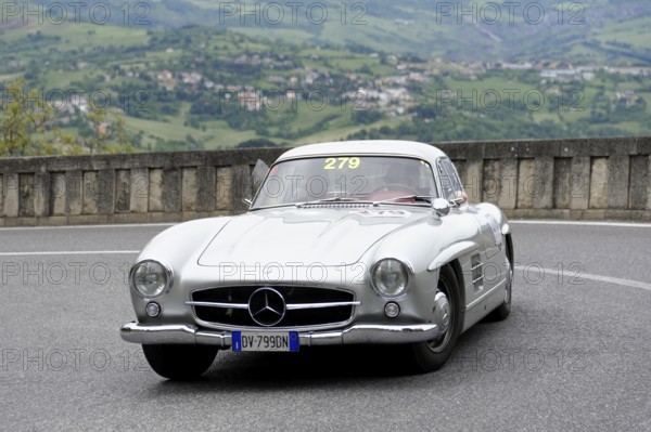 No.279, Mercedes-Benz 300 SL W 198, model year 1954, Silver vintage car driving on a winding road with mountain landscape in the background, Mille Miglia 2014 or 1000 Miglia, vintage car race, San Marino, Italy
