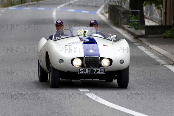 No. 287, Arnolt Bristol Bolide, built in 1954, A white vintage convertible with a blue stripe is driven by two drivers on a road, Mille Miglia 2014 or 1000 Miglia, vintage car race, San Marino, Italy