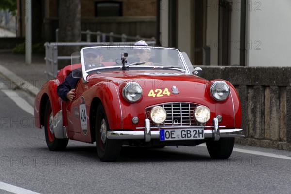 No.424, Triumph TR 3 Sports, built in 1956, A red vintage convertible with two people and round headlights drives along a country road, Mille Miglia 2014 or 1000 Miglia, vintage car race, San Marino, Italy