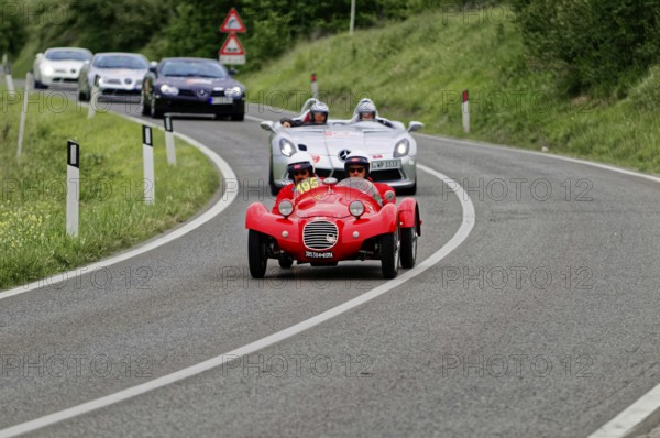 Two people with helmets in a red classic car on a country road, sporty-classic scene, classic car, car race, Mille Miglia, 1000 Miglia, 2015, Tuscany, Rome Lake Garda, Italy