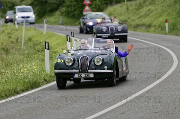 Two people in a green vintage convertible on a winding country road, casual atmosphere, vintage car, car race, Mille Miglia, 1000 Miglia, 2015, Tuscany, Rome Lake Garda, Italy