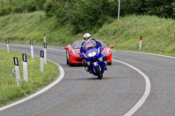 Blue motorbike takes a bend in front of a red Ferrari convertible on a country road, classic car, car race, Mille Miglia, 1000 Miglia, 2015, Tuscany, Rome Lake Garda, Italy