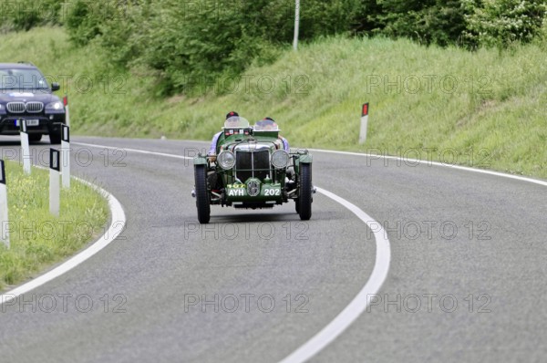 Green vintage car drives on winding country road, lined with green landscape, vintage car, car race, Mille Miglia, 1000 Miglia, 2015, Tuscany, Rome Lake Garda, Italy