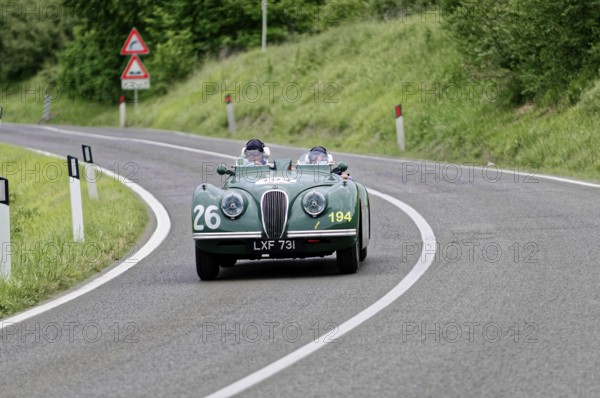 Two people in a green vintage convertible with racing numbers, fast drive on country road, vintage car, car race, Mille Miglia, 1000 Miglia, 2015, Tuscany, Rome Lake Garda, Italy