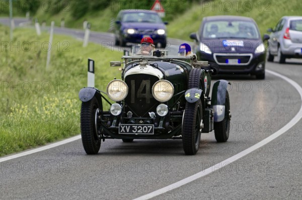 A classic vintage car drives in a rally on a winding country road through green surroundings, vintage car, car race, Mille Miglia, 1000 Miglia, 2015, Tuscany, Rome Lake Garda, Italy