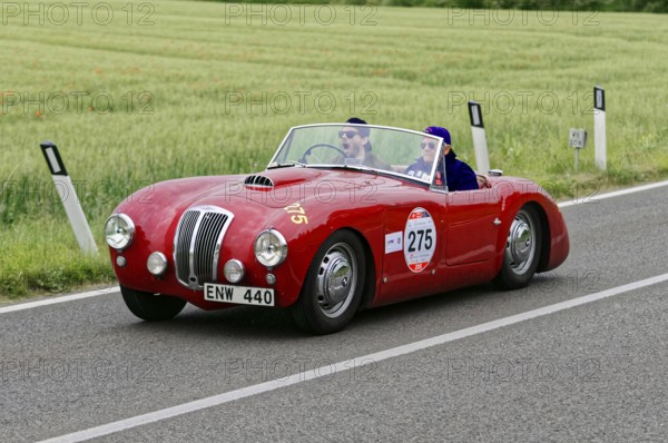 Red classic car on a country road in a vast green environment, classic car, car race, Mille Miglia, 1000 Miglia, 2015, Tuscany, Rome Lake Garda, Italy