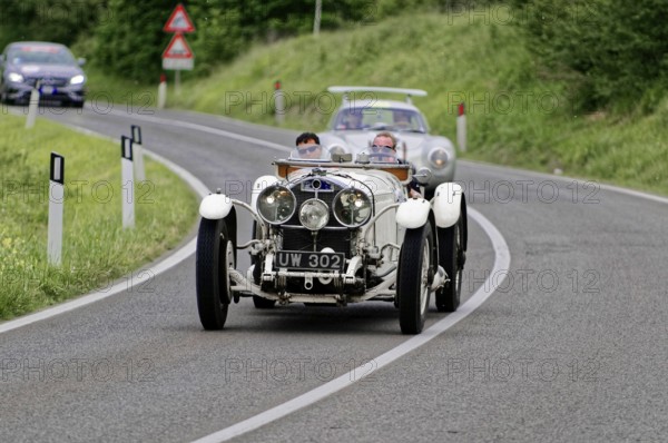 White classic car drives along a winding country road through a green landscape, classic car, car race, Mille Miglia, 1000 Miglia, 2015, Tuscany, Rome Lake Garda, Italy