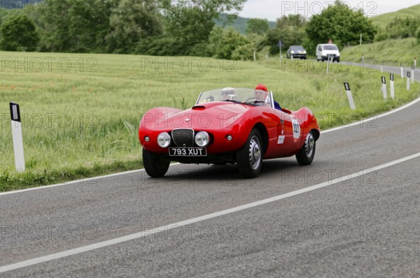 A sporty red classic car drives on an idyllic country road in a green landscape, classic car, car race, Mille Miglia, 1000 Miglia, 2015, Tuscany, Rome Lake Garda, Italy