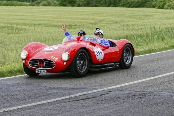 Two people joyfully driving a red Maserati on a country road, classic car, car race, Mille Miglia, 1000 Miglia, 2015, Tuscany, Rome Lake Garda, Italy