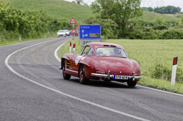 Rear view of a red Mercedes classic car driving on a winding road in a rural setting, classic car, car racing, Mille Miglia, 1000 Miglia, 2015, Tuscany, Rome Lake Garda, Italy