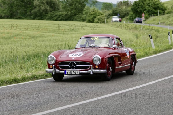 A red Mercedes classic car drives along a picturesque country road surrounded by trees, classic car, car race, Mille Miglia, 1000 Miglia, 2015, Tuscany, Rome Lake Garda, Italy