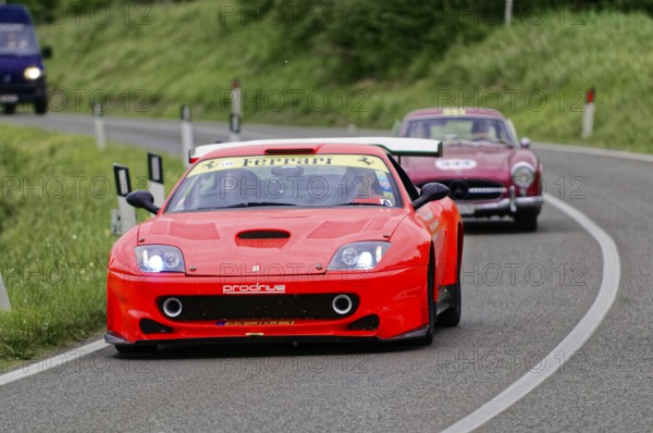 A red Ferrari racing car drives dynamically in front of a classic car, classic car, car race, Mille Miglia, 1000 Miglia, 2015, Tuscany, Rome Lake Garda, Italy