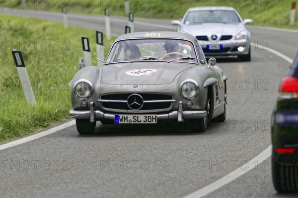 A silver vintage Mercedes car drives in front on a road, followed by another car, vintage car, car race, Mille Miglia, 1000 Miglia, 2015, Tuscany, Rome Lake Garda, Italy