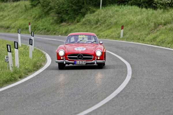 A red Mercedes classic car drives elegantly through a winding country road, classic car, car race, Mille Miglia, 1000 Miglia, 2015, Tuscany, Rome Lake Garda, Italy