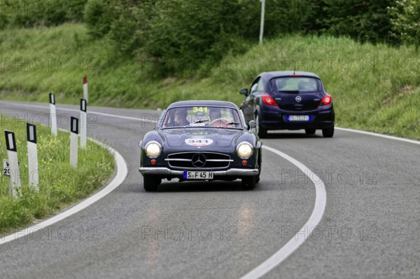 A black Mercedes vintage car drives a small car on a country road, vintage car, car race, Mille Miglia, 1000 Miglia, 2015, Tuscany, Rome Lake Garda, Italy
