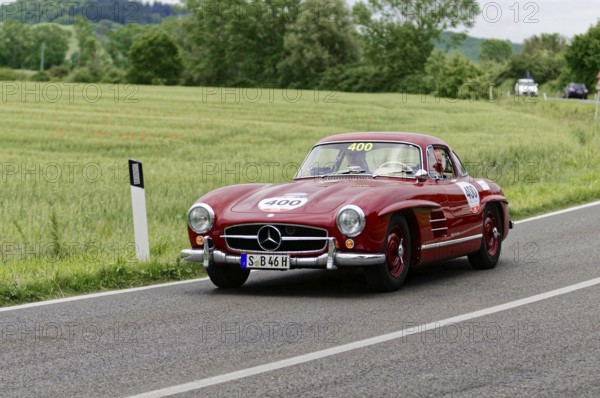 The red Mercedes classic car continues its journey on the sweeping country road, classic car, car race, Mille Miglia, 1000 Miglia, 2015, Tuscany, Rome Lake Garda, Italy