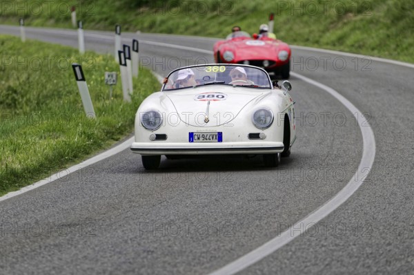 A white Porsche convertible in classic car style drives on a winding country road in front of a red car, classic car, car race, Mille Miglia, 1000 Miglia, 2015, Tuscany, Rome Lake Garda, Italy