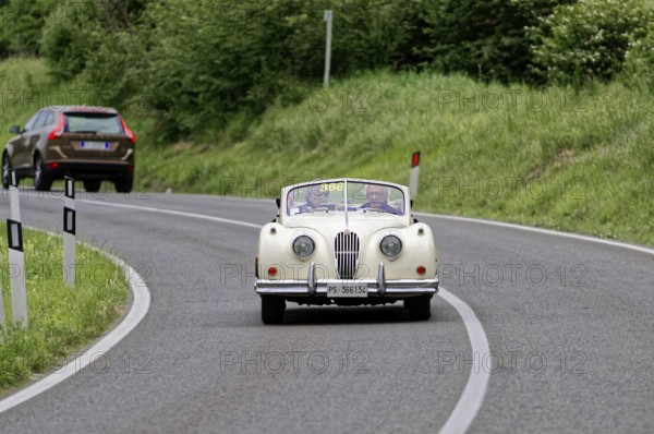A classic convertible drives along a winding country road surrounded by green countryside, classic car, car racing, Mille Miglia, 1000 Miglia, 2015, Tuscany, Rome Lake Garda, Italy