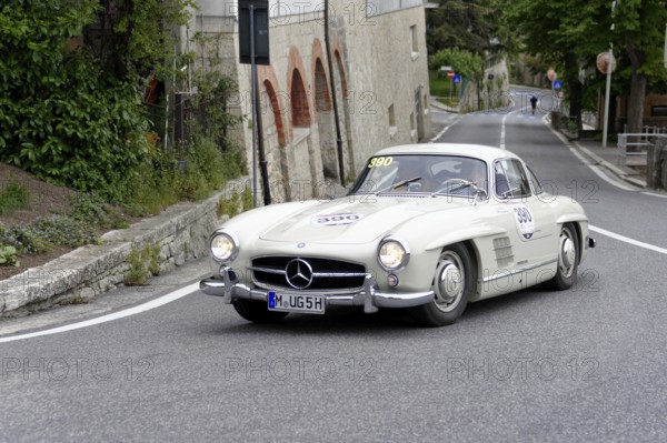 No.390, Mercedes-Benz 300SL W 198, model year 1955, White Mercedes vintage car driving on a winding urban road, Mille Miglia 2014 or 1000 Miglia, vintage car race, San Marino, Italy