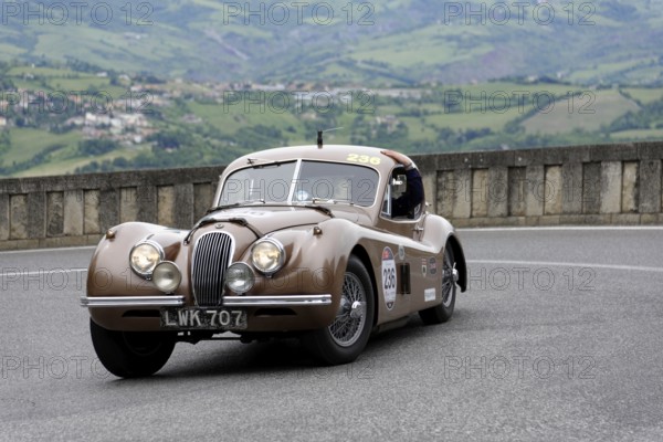 No. 236, Jaguar XK 120 Coupé, built in 1952, Brown vintage car on winding road with picturesque mountain landscape in the background, Mille Miglia 2014 or 1000 Miglia, classic car race, San Marino, Italy