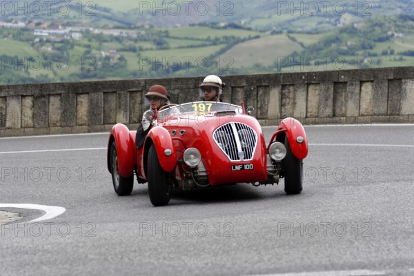 No.197, Healey 2400 Silverstone, built in 1950, red car with two occupants in classic helmets on a winding road, Mille Miglia 2014 or 1000 Miglia, classic car race, San Marino, Italy