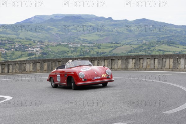 Red open-top sports car on a winding track in a picturesque mountain landscape, Mille Miglia 2014 or 1000 Miglia, classic car race, San Marino, Italy