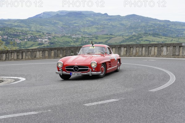 No. 334, Mercedes-Benz 300 SL W 198, model year 1955, Red classic sports car rounding the bend in a green hilly landscape, Mille Miglia 2014 or 1000 Miglia, classic car race, San Marino, Italy