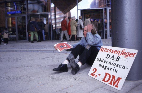 Berlin, DEU, 18.10.1998 -- Chris, seller of a homeless magazine Straßenfeger, sits in front of the casino at Potsdamer Platz arcades. (poverty)