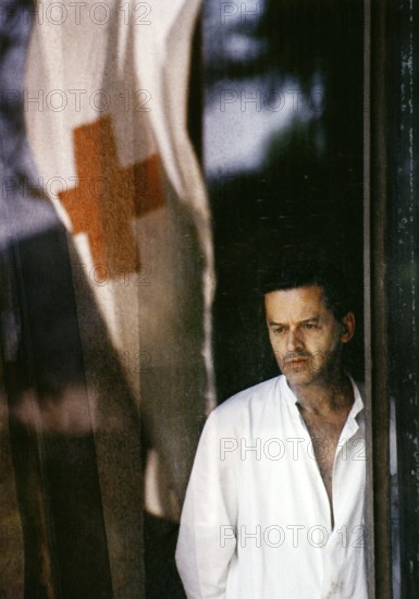 BIH, Bosnia, Sarajevo, 07.09.1992, A doctor looks through the window of the Kosevo Hospital, in which a Red Cross flag is reflected