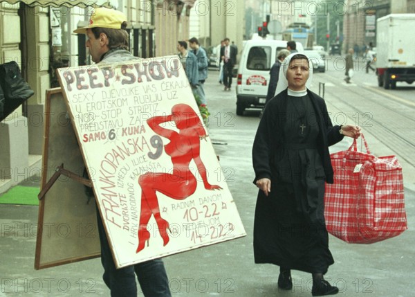 HRV, Zagreb, 01.05.1995 -- A Catholic nun meets a sex shop advertiser in Zagreb. -- A catholic now passes an advert for a sex show in downtown Zagreb. Eastern Europe, Eastern Europe, Balkans, Croatia