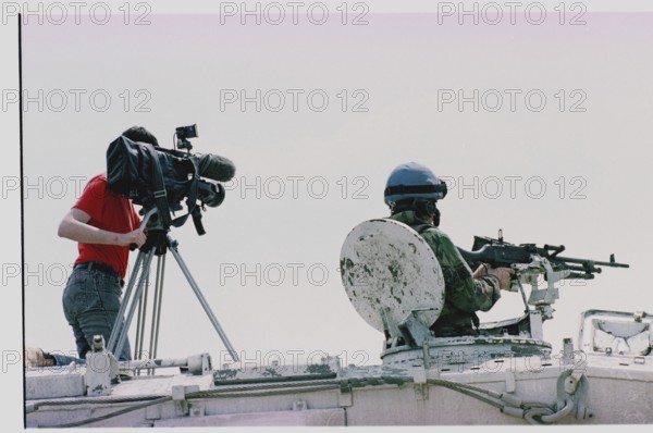BIH, Tuzla, 01.05.1993 -- A cameraman and a British UN soldier wait for refugees from Srebrenica to arrive at Tuzla airfield. -- A cameraman stands next to a British UN soldier ontop of an APC at Tuzla airport, as they wait for the arrival of Muslim refugees out of Srebrenica. Bosnia Hercogovina, Eastern Europe