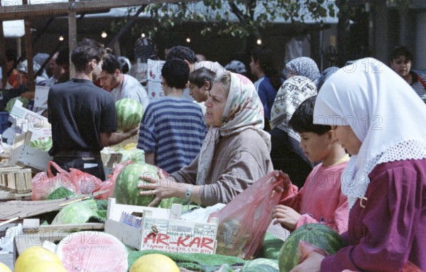Berlin, DEU, 10.06.1998 -- Hustle and bustle on a Turkish market, salespeople wearing headscarves at a melon stand. (Retail, fruit)