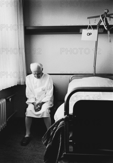 Berlin, DEU, 17.05.1998 -- ENT department, a patient (82 years old) sits next to his hospital bed with an OP sign. (hospital, operation)