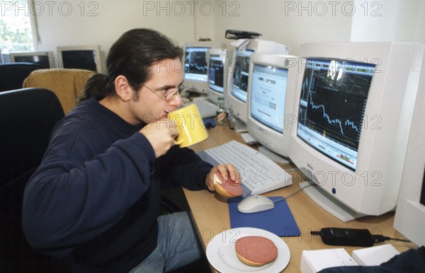 Berlin, DEU, 29.09.1999 -- Day trader Schrader treats himself to a quick bite while he continues to watch the business.