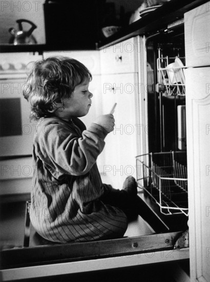 DEU, Meudt, 10.09.1999 -- From the series -- LINUS --- Linus on the dishwasher door. (dishwasher, curiosity) (demography, child)