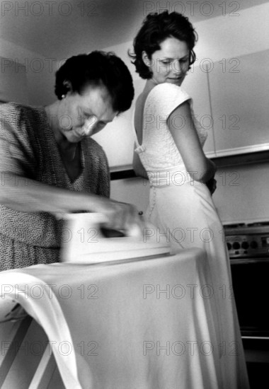 DEU, Westerburg, 09.09.1999 -- Mother of the bride irons the last wrinkles out of the bride's dress. (ironing, iron, ironing board, cloth, hurry, marriage)