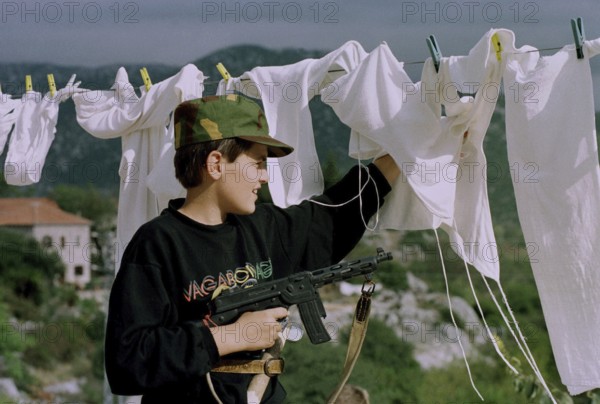 HRV, Kraotien, Dubrovnik 20.09.1993 Child with toy gun behind laundry. HRV Croatia, Dubrovnik, 1993 09 20 Kid with Toygun Behind Laundry