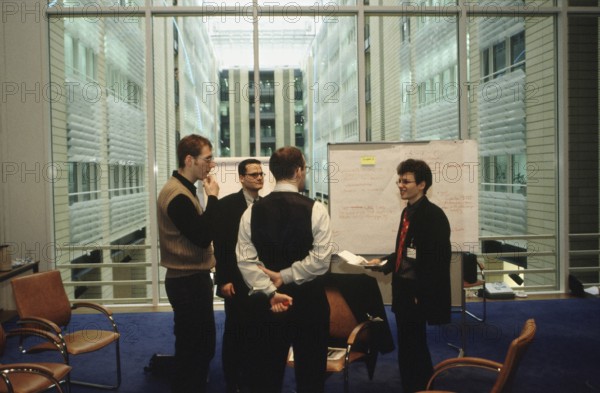 Berlin, DEU, 15.01.1999 -- Debis-Campus meets company, event - a group of male workshop participants discussing in front of an information/work wall in a conference room in the Debis House on Potsdamer Platz.