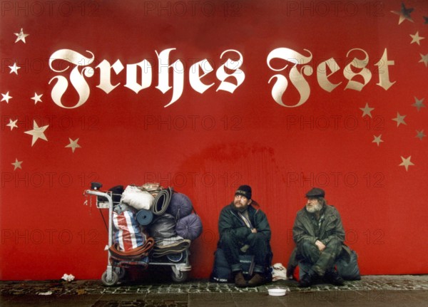DEU, Frankfurt/Main, 13.12.99 -- Two homeless people are begging under the inscription Frohes Fest. (stars, writing, sitting)