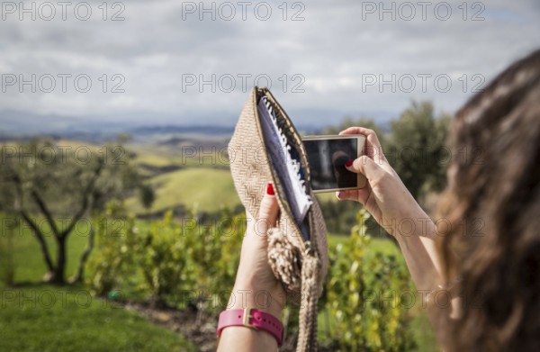 ITA Italy Castelfalfi A woman takes a photo with her smartphone on the hotel terrace