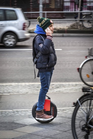 DEU Germany Germany Berlin A teenager makes phone calls with his smartphone while driving an air wheel across Yorckstraße