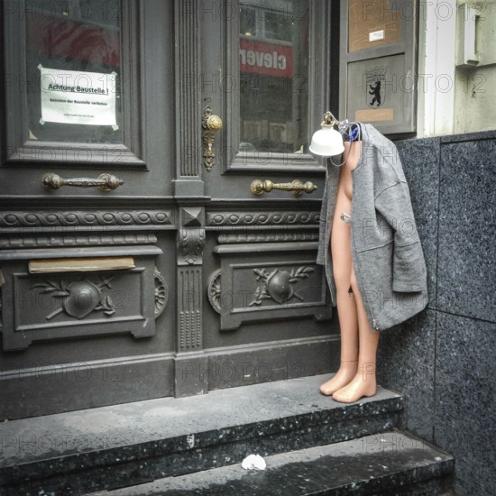 DEU Germany Germany Berlin Half a shop window doll is standing, decorated with lamp and mantle, in an entrance on Joachimsthaler Straße in Wilmersdorf