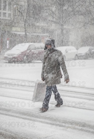 DEU Germany Germany Berlin People in the city during a snow shower.Pedestrian crosses snowy road