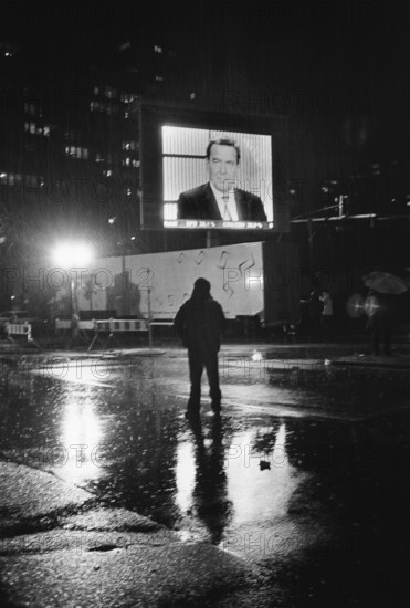DEU, Germany, Berlin, 22.09.2002, Man in the rain watching Gerhard Schröder on a large screen
