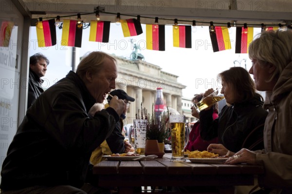 DEU Germany Berlin Eating and drinking in front of the Brandenburg Gate. Scene on the eve of the 20th anniversary of German reunification on the festival mile in Berlin. Germany Berlin People taking a snack in front of Brandenburg Gate. Scene from the public party one day ahead of the celebration marking the 20th anniversary of the German reunification