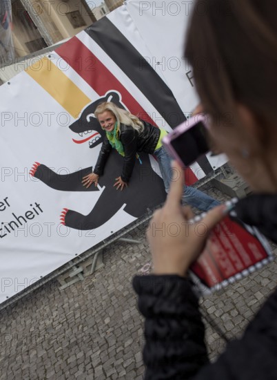 DEU Germany Berlin Girls take pictures of themselves in front of a poster with the Berlin Bear. Scene on the eve of the 20th anniversary of German reunification on the festival mile in Berlin. Germany Berlin Women taking picture with Berlin Bear. Scene from the public party one day ahead of the celebration marking the 20th anniversary of the German reunification