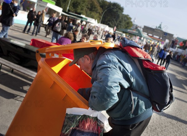 DEU Germany Berlin A collector checks the garbage cans for recyclable materials. Scene on the eve of the 20th anniversary of German reunification on the festival mile in Berlin. Germany Berlin A poor digs in a dustbin at the party for the reunification. Scene from the public party one day ahead of the celebration marking the 20th anniversary of the German reunification