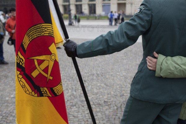 DEU Germany Berlin Actor with GDR flag is hugged by tourists while taking pictures. Scene on the eve of the 20th anniversary of German reunification on the festival mile in Berlin. Germany Berlin Actor with GDR flag get huged while beeing pictured at Parser Platz. Scene from the public party one day ahead of the celebration marking the 20th anniversary of the German reunification
