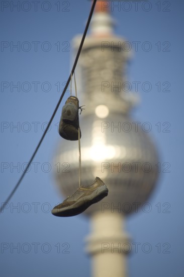 GERMANY Berlin shoes on a power line with a view of Alex. Germany Berlin Shoes are hanging over an electric wire near the TV Tower Alex